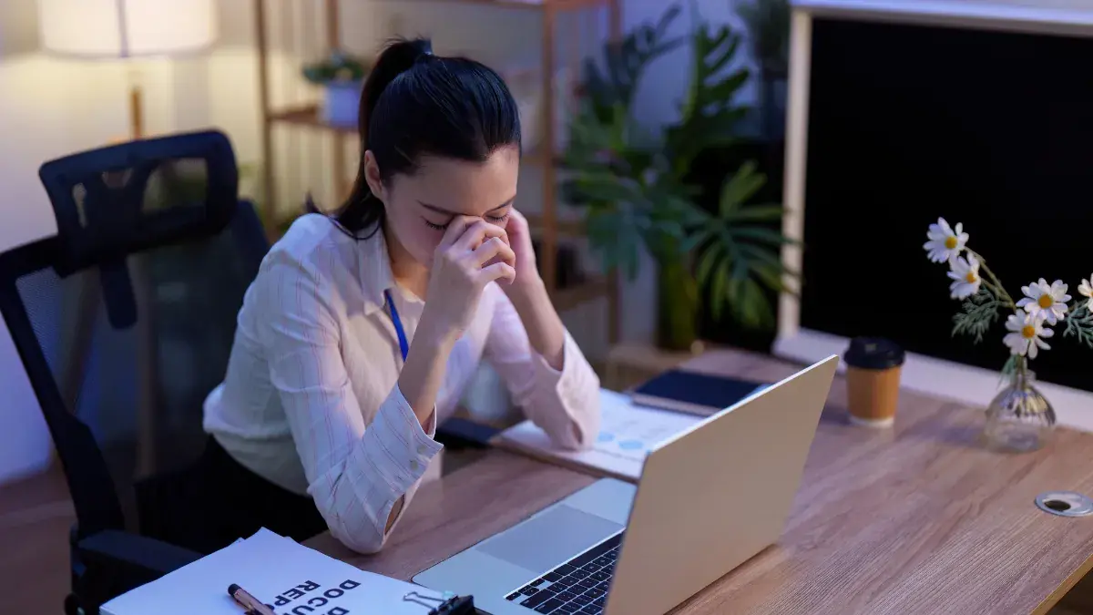 夜間坐在辦公桌前使用筆電並顯得疲憊的亞洲女性