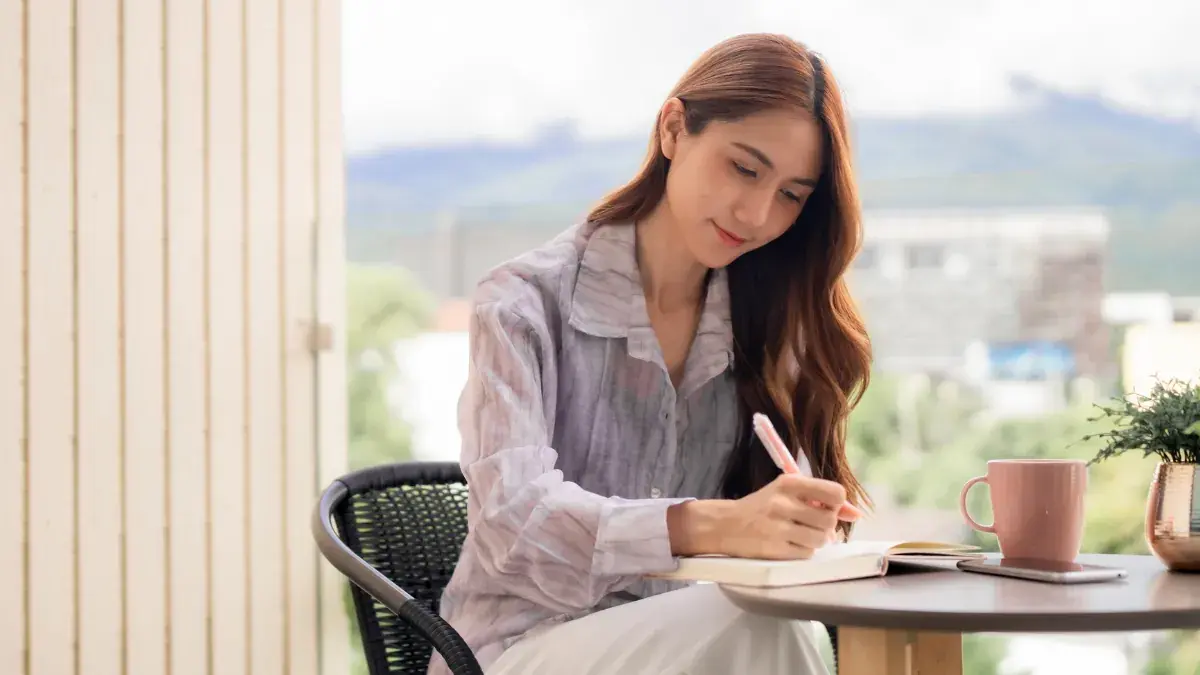 坐在陽台桌邊書寫筆記本的亞洲女性