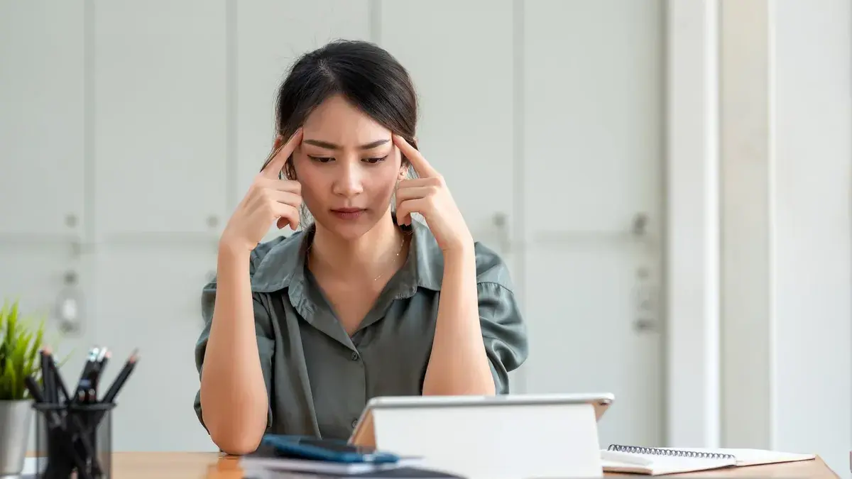 亞洲女性坐在辦公桌前思考中年職涯方向
